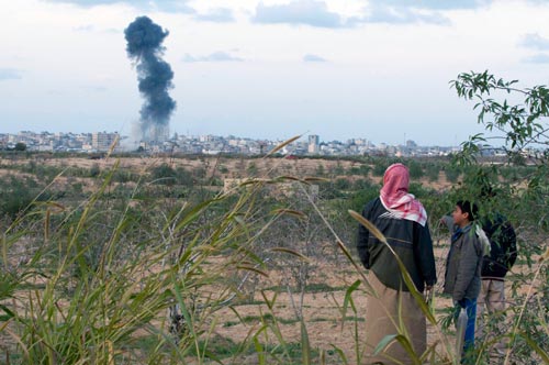 A father and son look on from a hilltop on the Egyptian side of the Rafah border terminal as Israeli jets bomb Rafah City, Gaza, on Friday, January 9.