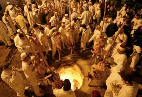 Lamb spits are lowered into the pit for roasting.