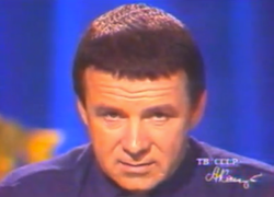 A man with a caesar haircut and a turtleneck stares into the camera.