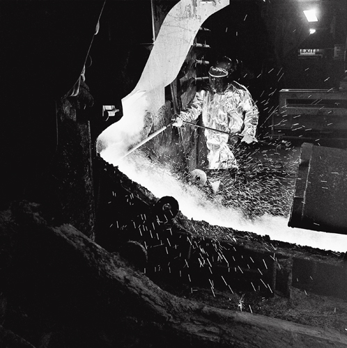 A furnace tapper using a thermal lance to test the purity of molten nickel. The furnace at the Falconbridge Smelter operates at over 1,000 degrees centigrade.