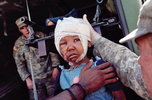 A sad little girl has her head bandaged, a scraped-up cheek, and one eye swollen shut.
