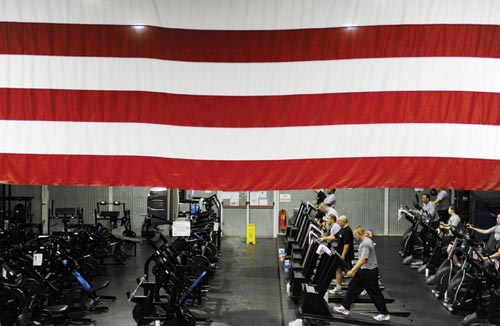 A large American flag hangs above a large room. It's full of exercise bikes, treadmills, and the usual execise equipment.