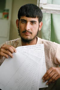 A young man holds up several hand-written pages.