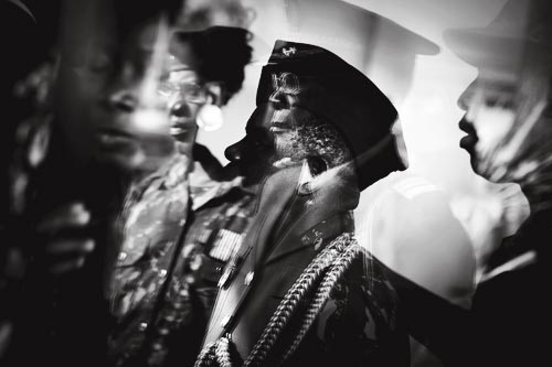 Decorated middle-aged soldiers, standing at attention, photographed in a double exposure.