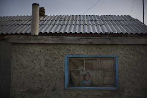 Six-year-old Daylet Ayaganov looks out the window of one of only twenty houses in Tactubek.