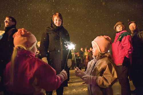 Ingibjörg S. Guðmundsdóttir watches her twin daughters at the annual New Year's bonfire.