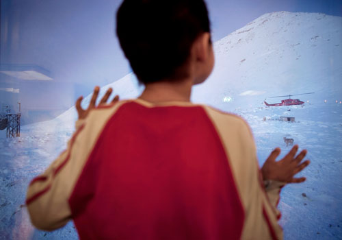 A helicopter arrives in Siorapaluk, Greenland's northernmost settlement, while Asiaq, eight, watches from his classroom window.