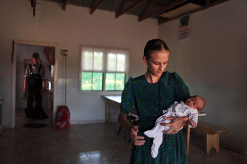 Maria Peters, fifteen, holds her newborn baby sister at their home in the Mennonite settlement of Manitoba, in eastern Bolivia.
