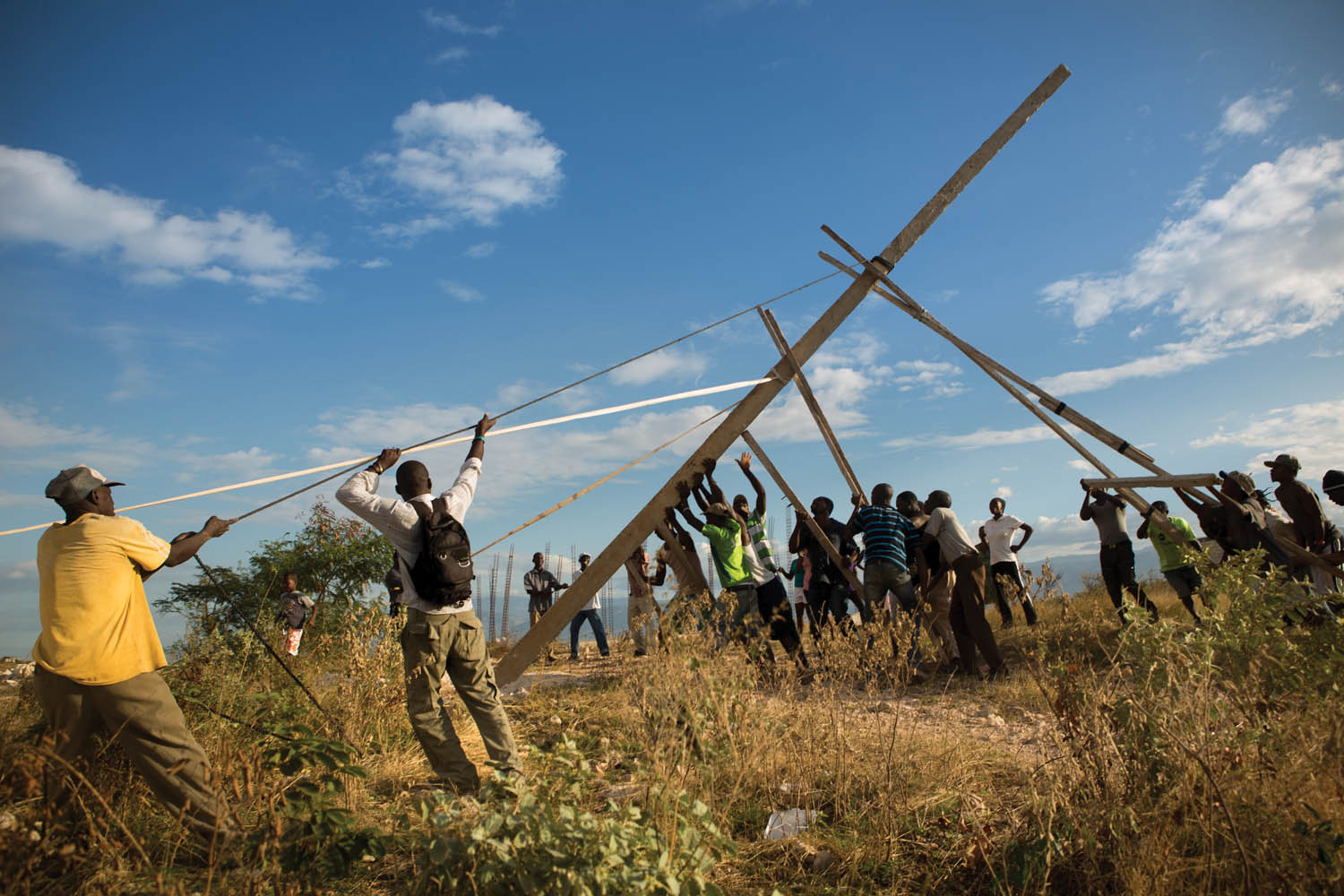 Residents of Canaan raise the first of three handmade utility poles, part of an improvised effort to receive electricity from the state power grid. Photo by Allison Shelley.