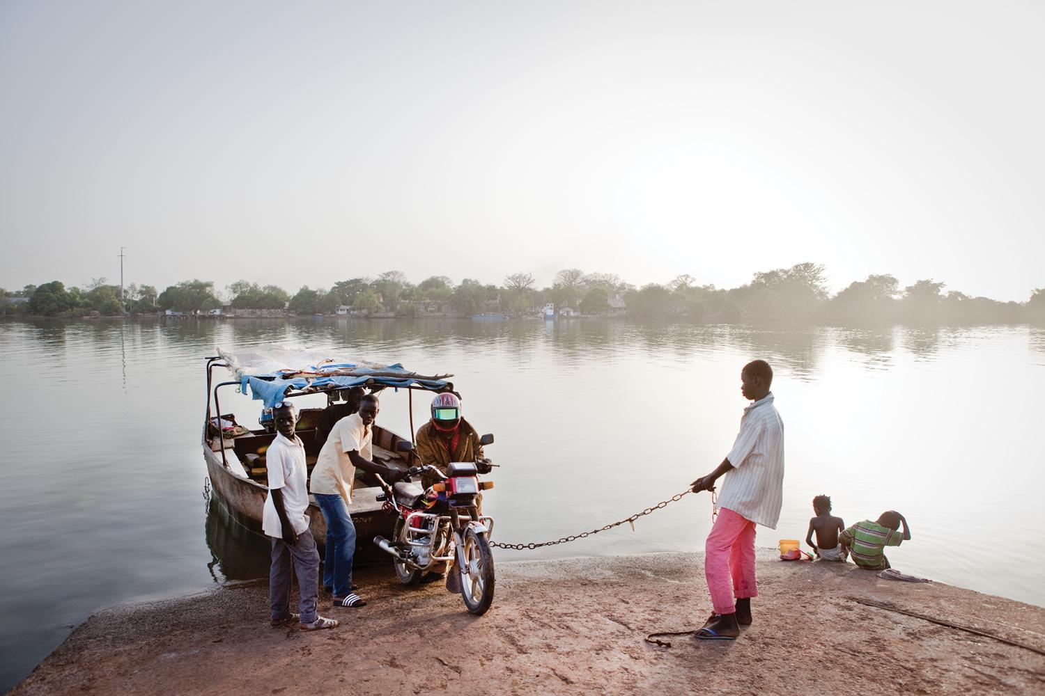Small metal ferries, called barras, are the main way to cross the Gambia River in the upcountry regions of the Republic of Gambia. Some barras are motorized, but most are rowed with a single paddle attached to the stern.