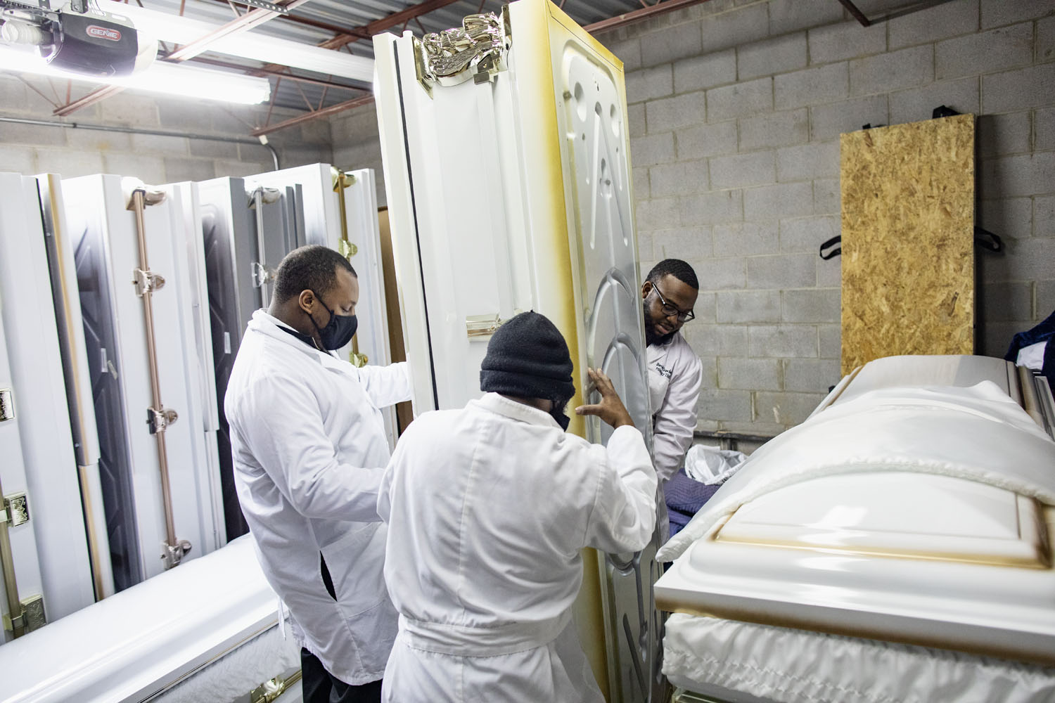 Workers move a casket in a storage room at Lucas Memorial Chapel. Garfield Heights, OH, April 2021.