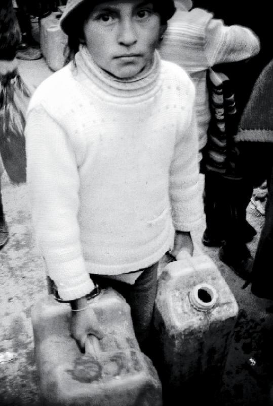 A child sells contaminated water trucked in from a nearby lake.