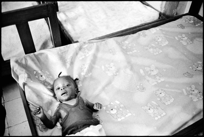 Six-month-old Pierre lies on a bed at the APROSIFA shelter. 