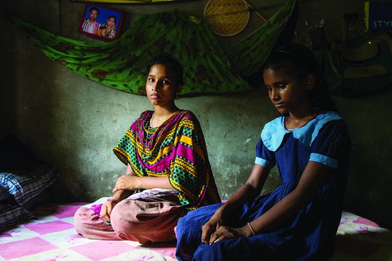 Latifa (left) and Arifa Rahman mourn the loss of their mother, Rina, in their one-room family home in Savar.