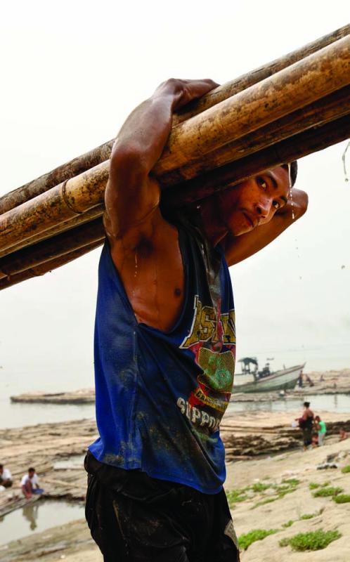A dockworker bearing bamboo shafts, Mandalay jetty. Photo by Jason Motlagh.