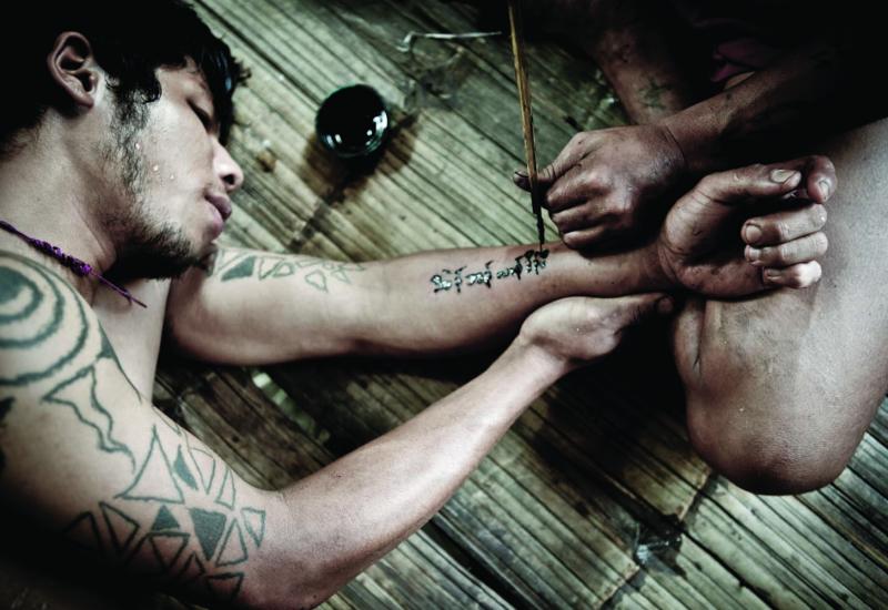 Soldiers at an undisclosed KNLA base tattoo each other using ink and sharpened stick. Many of the Karen believe that certain symbols will act as amulets and protect them in battle.
