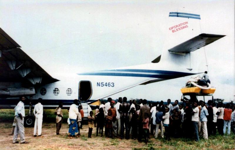 Curious villagers in Zaire (now Congo) watch a diamond-mining dredge being loaded onto a plane dispatched to Africa by Robertson’s in-ternational charity, Operation Blessing, in the mid-1990s.