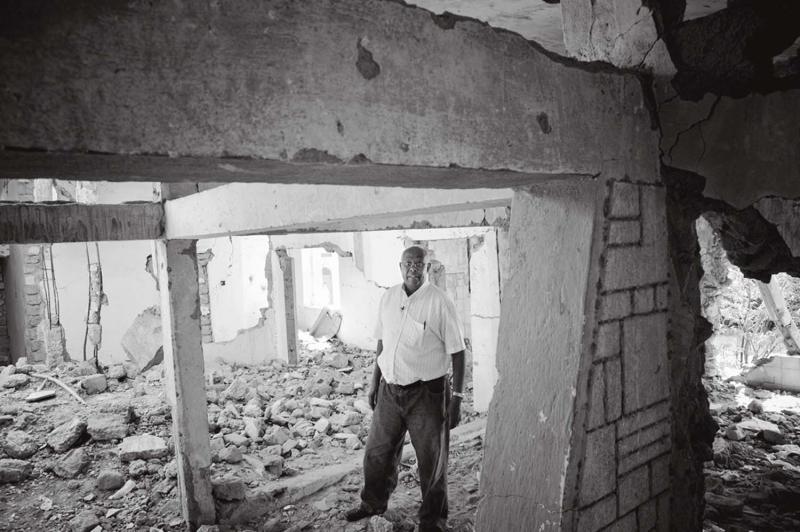 Dr. Aden Ismail stands in the ruins of his former mater- nity clinic. After the war, he qualified as a psychiatrist and returns now each year to treat those suffering from post-traumatic stress disorder.
