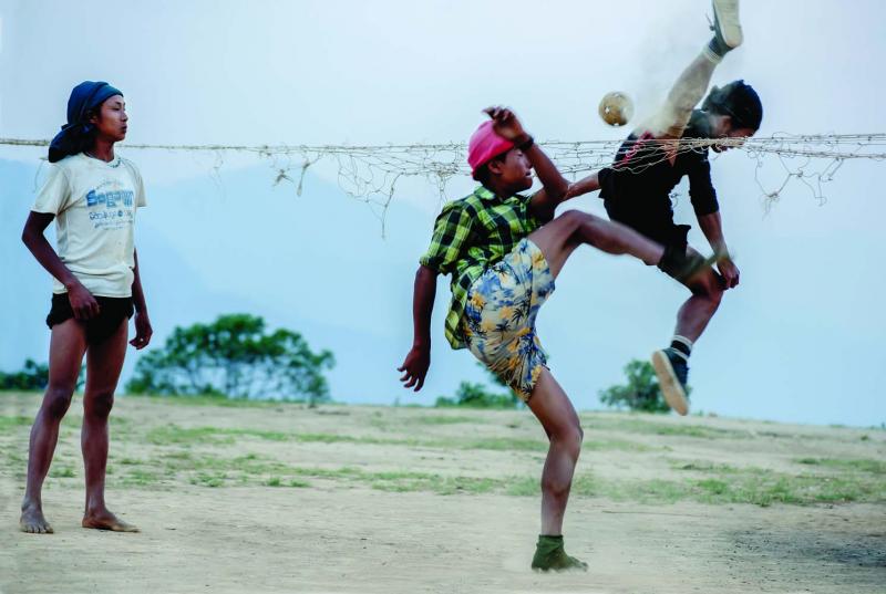 Boys play cane ball, a cross between soccer and volleyball, with a rattan ball on the plateau overlooking the valley below Layshee.