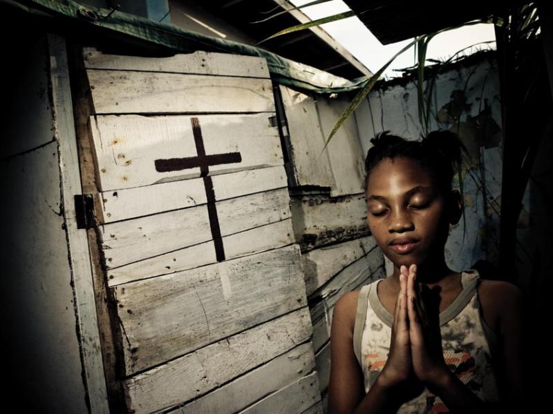 Annesha Taylor’s daughter prays at an altar constructed in their backyard in Arnett Gardens in Kingston.