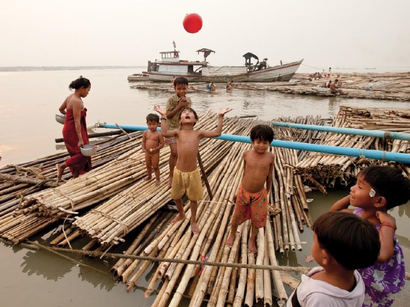 Children play ball on a bamboo raft along the Mandalay quai. Lashed together upriver, the makeshift rafts are floated down to the boomtown and used as construction scaffolding. Photo by Jason Motlagh.