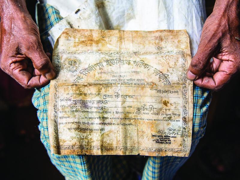 Lutfer Rahman holds the document that his daughter found next to the body of his wife, Rina Rahman, confirming her death in the collapse. (All photographs by Jason Motlagh)