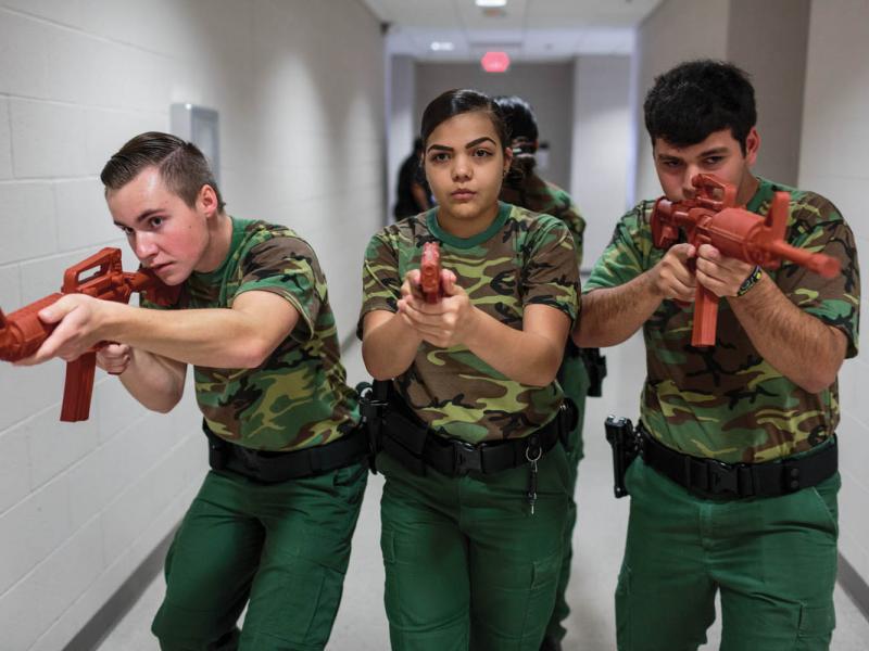 Ryan Dunlavy (left), Nerisa Garcia (center), and Jeremy Cabral (right), students from the Border Patrol Explorer Program, practice active-shooter scenarios and room clearing at the United States Border Patrol Station in Kingsville, TX. The Explorer program is a branch of the Boy Scouts of America and is sponsored by the US Department of Homeland Security. Photographed by Sarah Blesener