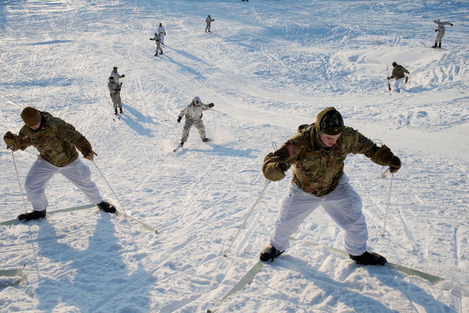 US solders (in green) struggle to learn how to scale a slope while training with Finnish soldiers. Sodankylä, Finland, February, 2023.