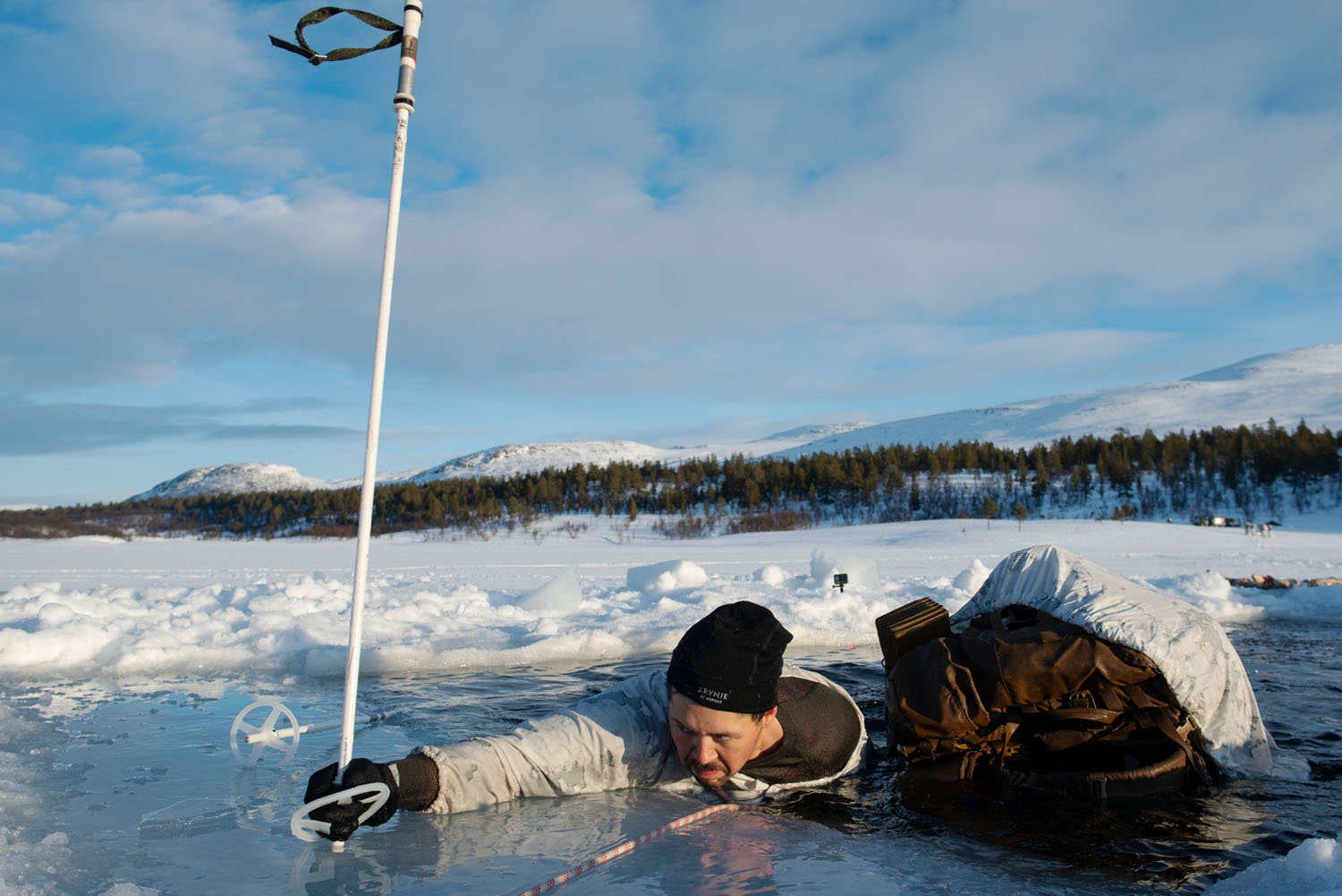 A US Marine struggles during a “through-the-ice” exercise, which includes wearing and recovering his skis while in the water. Norway, January, 2020.