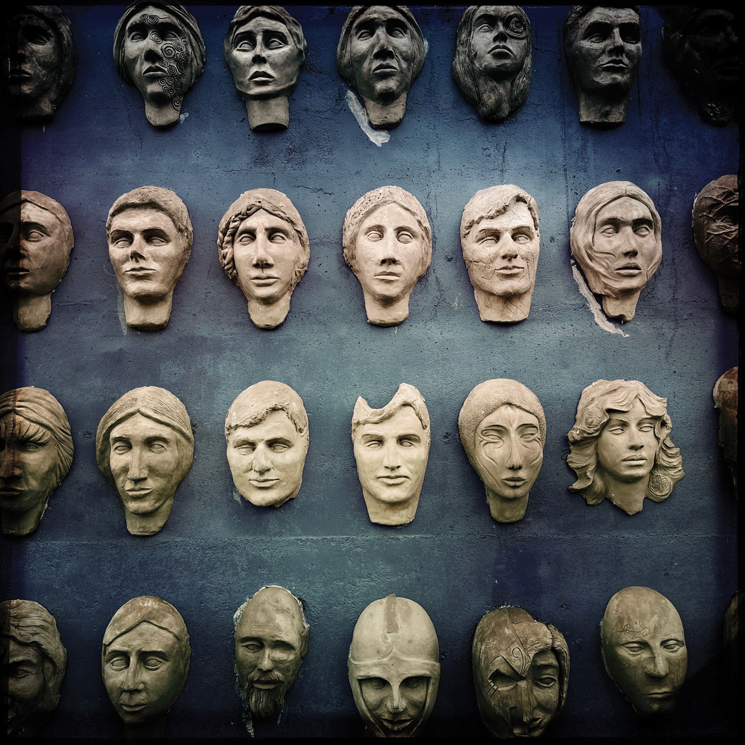 Stone busts mounted on wall as art installation in Librino, Sicily. 