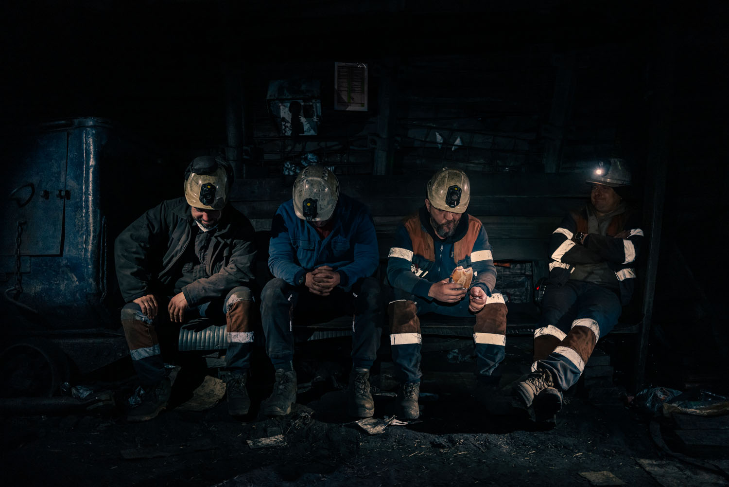 4 men sitting on a bench in uniform in a dark cave