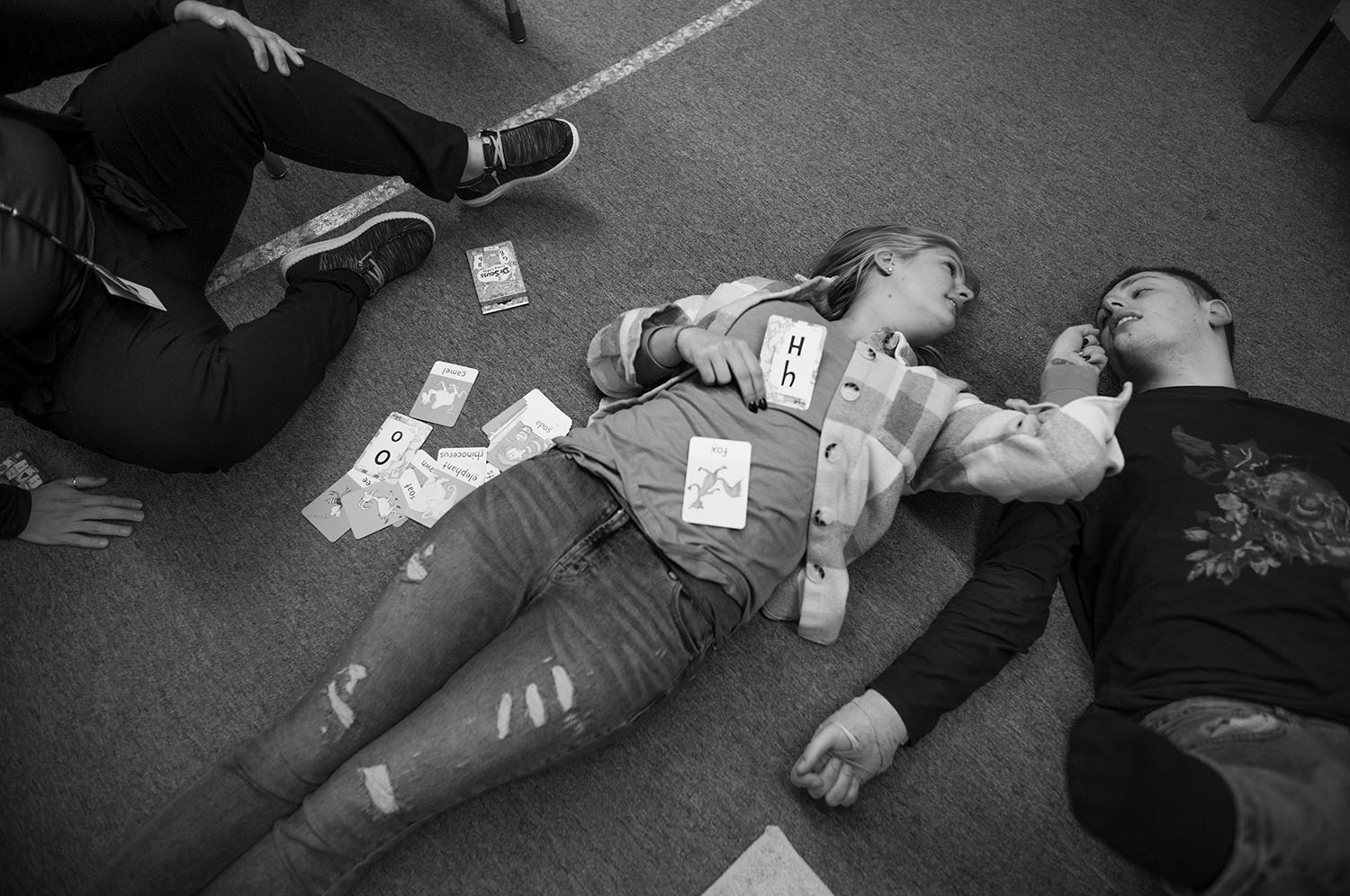 Woman and boy lie on floor covered in cards.