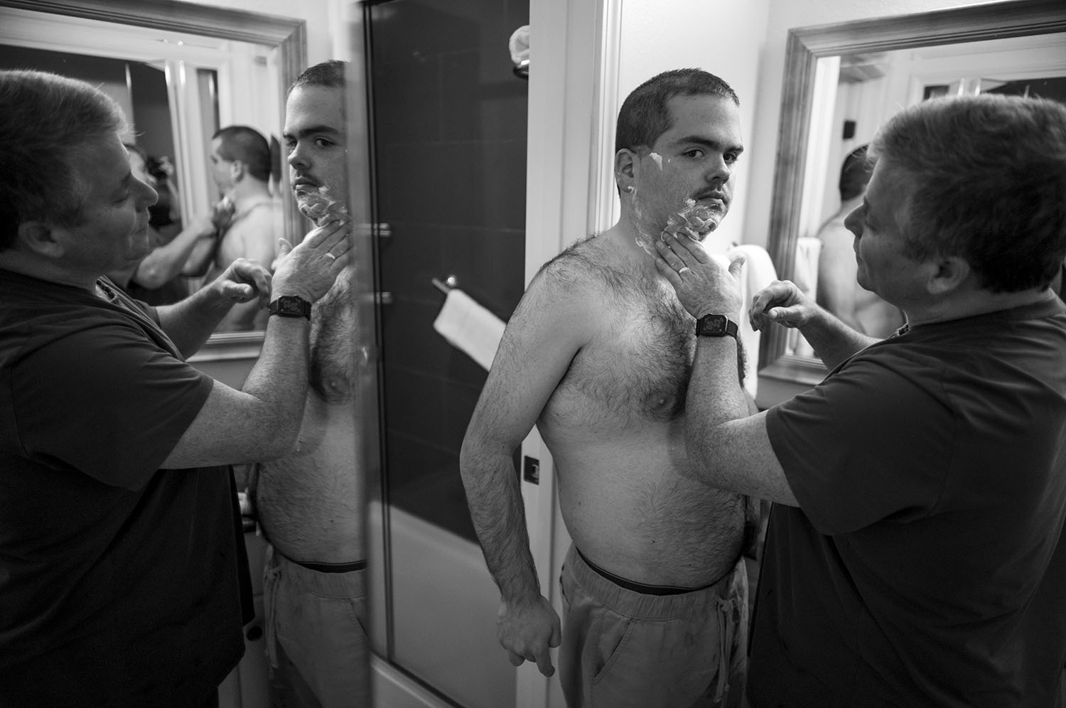 Man puts shaving cream on boy's face.