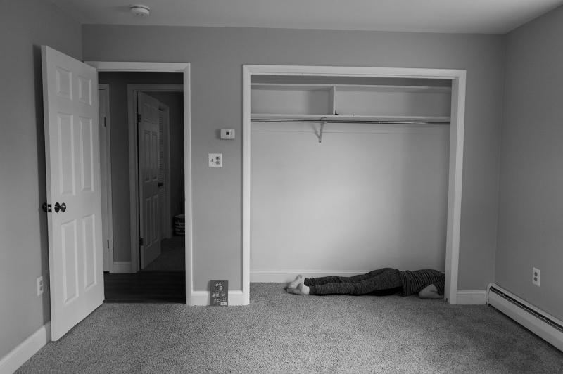 Boy lies in empty closet.