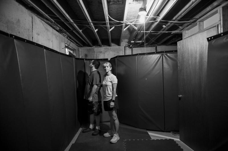 Man and woman stand in padded room.