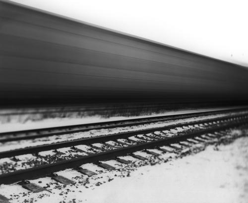 Blurry train passing with open tracks in the foreground.