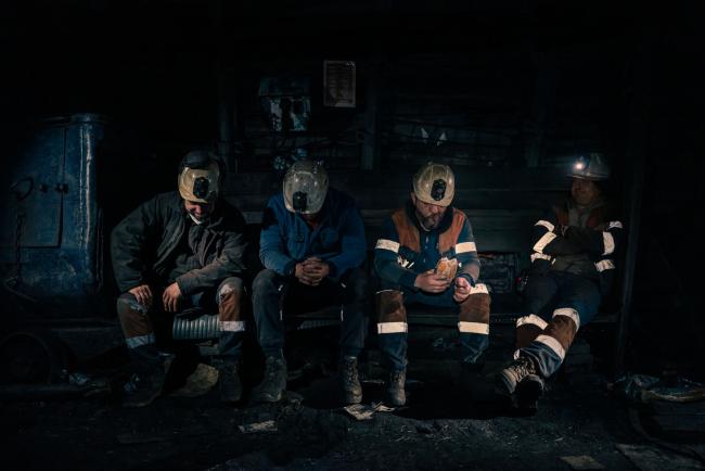 4 men sitting on a bench in uniform in a dark cave
