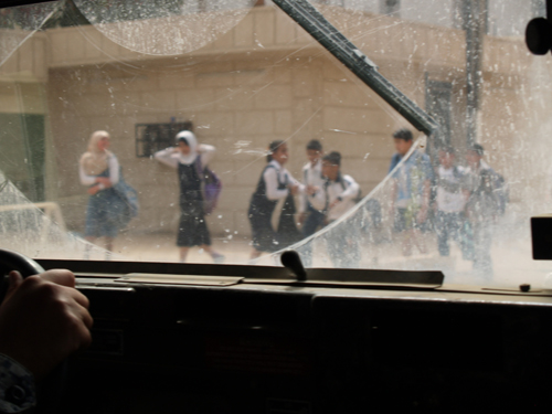 A view of a Baghdad street through a dirt-caked windshield.