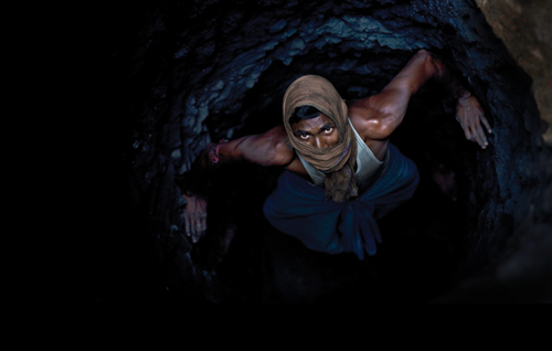 A man crawls through a deep mine. The constant coal fires in Jharia send underground temperatures soaring.
