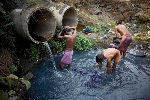 Young men bathe and wash their clothes after a day of scavenging coal.