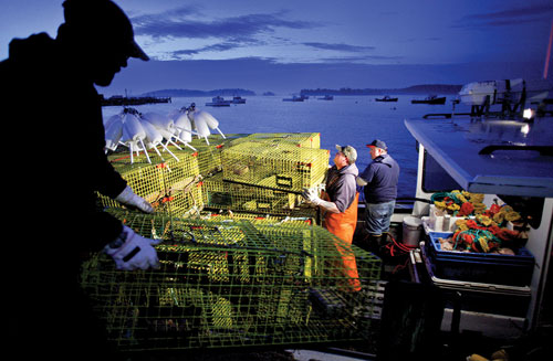 Captain Rick Trundy and sternman Lance Friend stack lobster traps and buoys aboard the Crossfire.