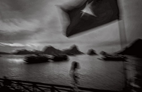 A tourist boat flies the Vietnamese Communist flag in Ha Long Bay.
