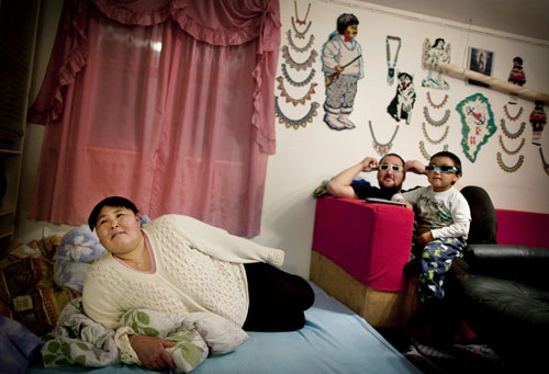 Ella, Salu, and their son Hans, four, watching a 3-D movie in their home in Isortoq.