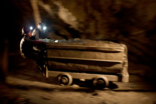 German Flores, seventeen, and Emiliano Mamani, twenty-four, ride a cart full of minerals to the exit of Candelaria Mine.