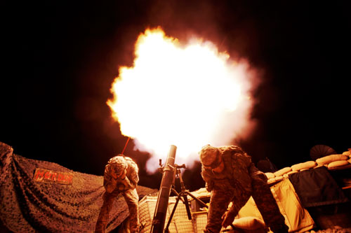 Soldiers from the US Army's 3rd Battalion, 509th Infantry Regiment (Airborne), based at Fort Richardson, Alaska, duck away from the blast of a 120mm mortar during a fire  mission at the combat outpost Zerok in East Paktika province in Afghanistan