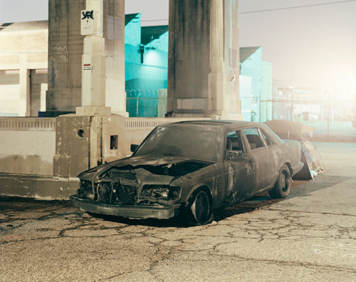 A burned car under the freeway.