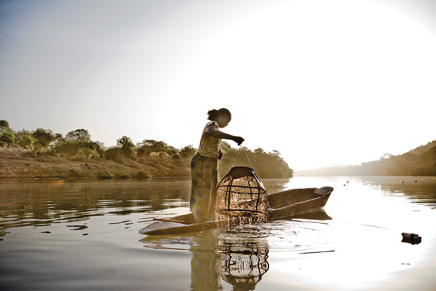 A migrant worker from Mali pulls up fishing pots from the river near the Gambian village of Fatoto.