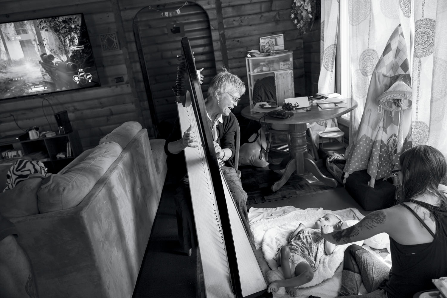 A musical therapy provider working with hospice plays the harp for Maddie. La Conner, WA, July 2018.