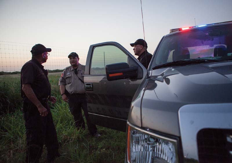 Members of the Brooks County Sheriff’s Department meet before searching an abandoned safe house on the outskirts of Falfurrias, Texas.