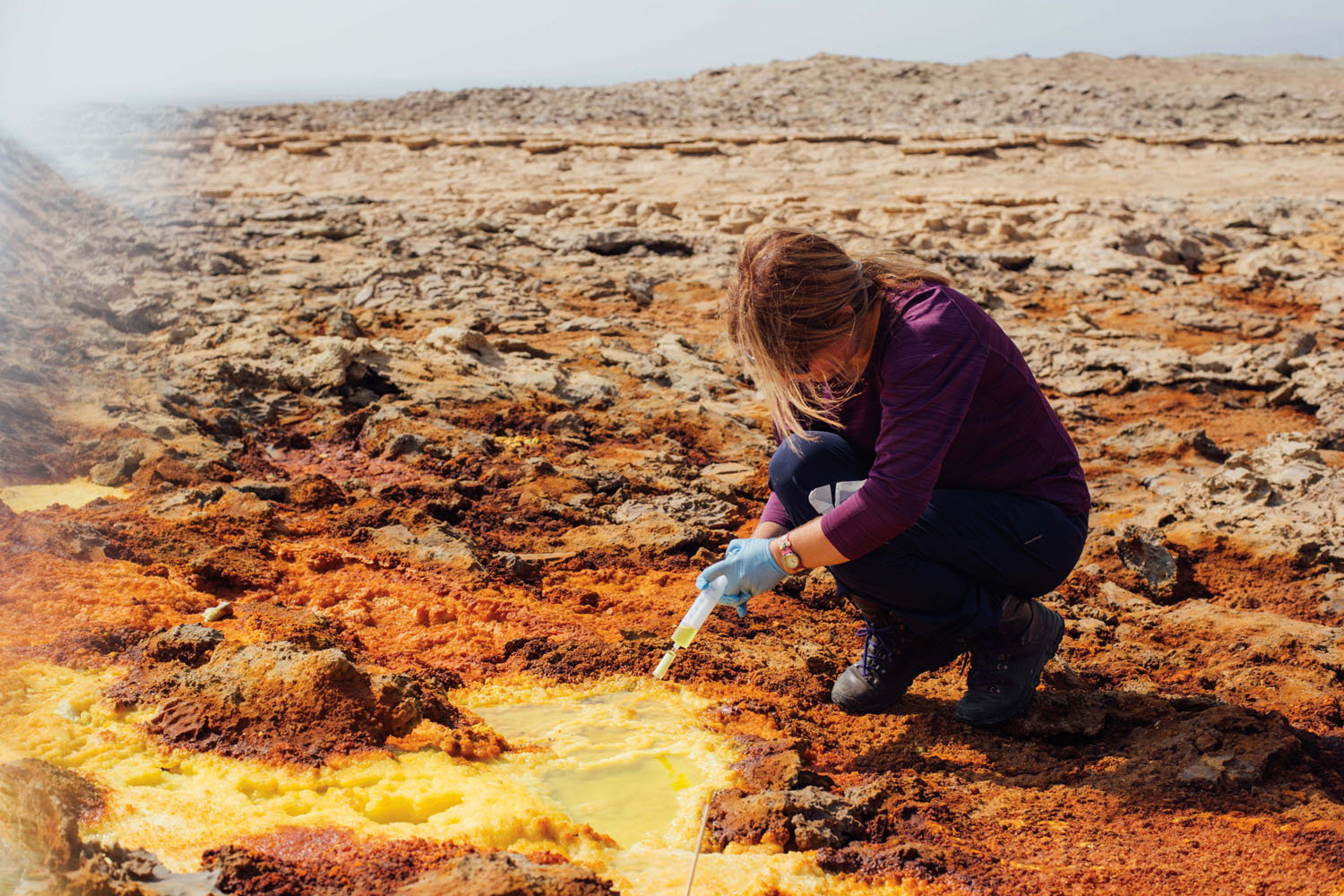 Dr. Karen Olsson-Francis collects a sample from a sulfur pool. These samples will be brought back to her lab in the United Kingdom, where her team will look for biosignatures that may provide clues about the extreme limits of life here on Earth as an analogue for extraterrestrial sites. Photograph by Alex Pritz.